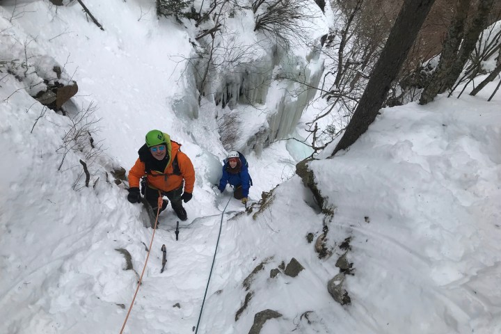 two people climbing up a snow covered slope