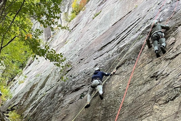people climbing up a rocky cliff